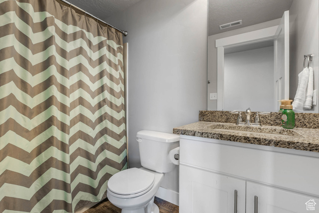 Full bath featuring vanity, a textured ceiling, wood finished floors, and a shower with curtain