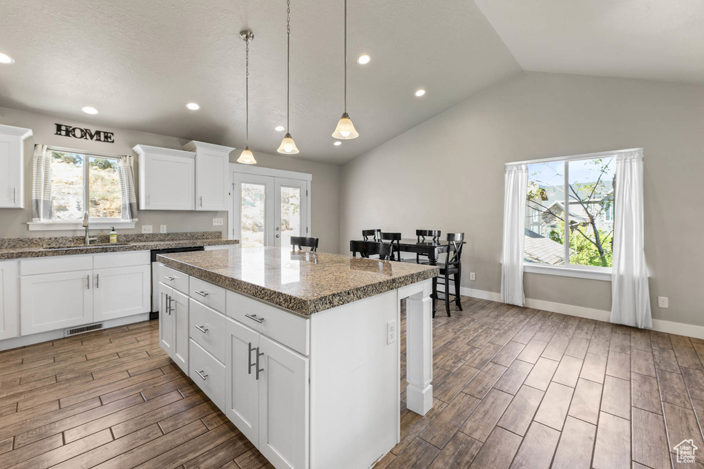 Kitchen featuring wood finished floors, a kitchen island, plenty of natural light, pendant lighting, and recessed lighting