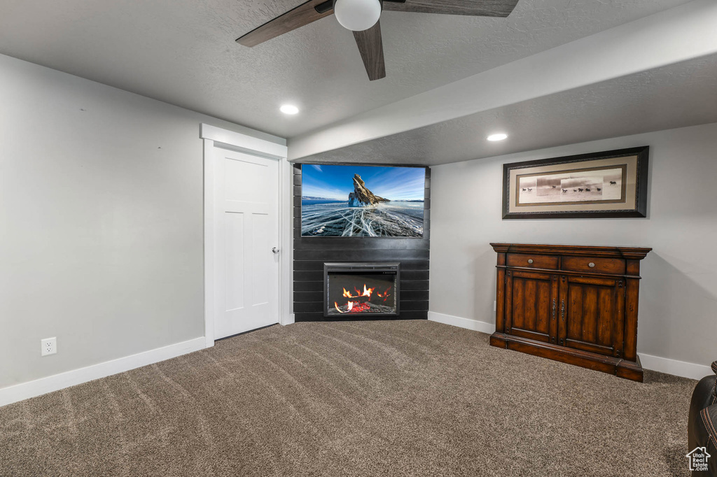 Carpeted living room with a fireplace, a textured ceiling, a ceiling fan, and recessed lighting