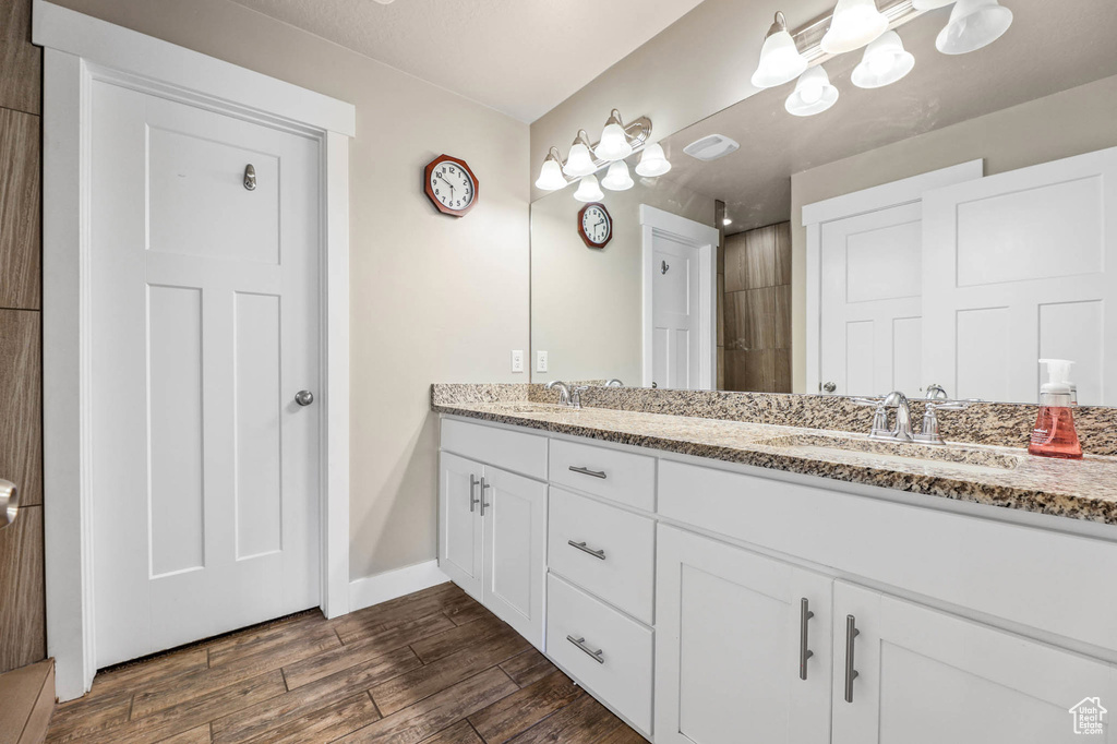 Bathroom featuring double vanity, wood finished floors, and tiled shower