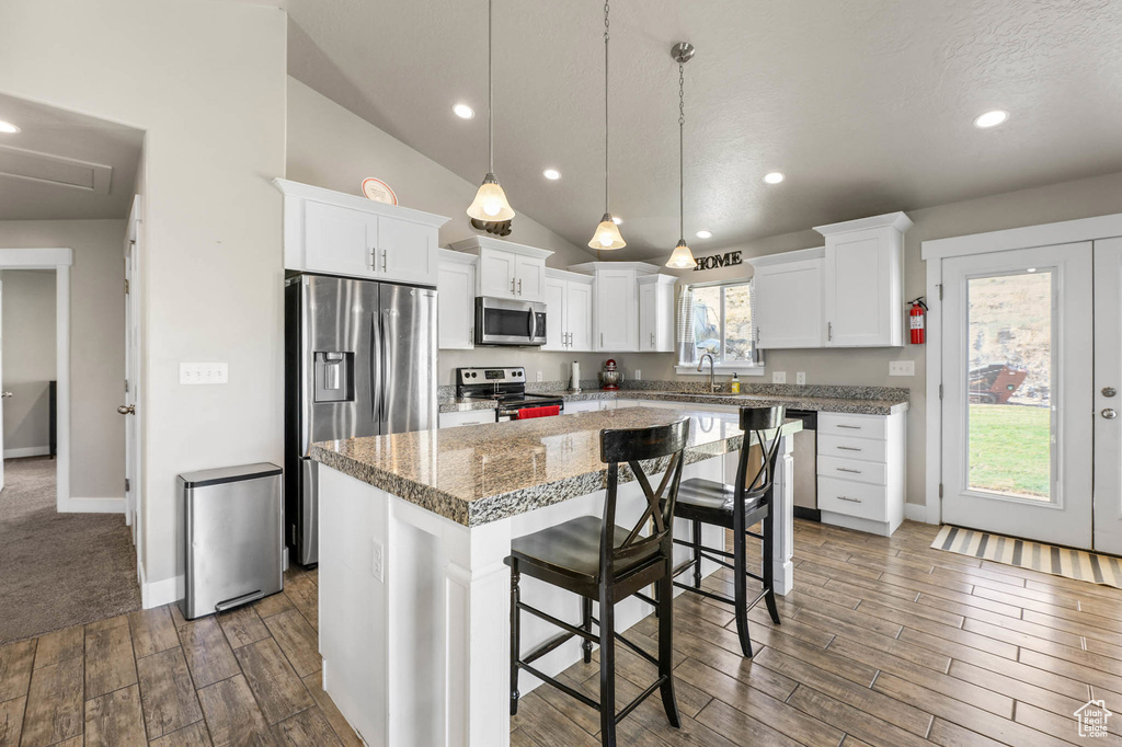 Kitchen with a center island, stainless steel appliances, dark wood-type flooring, white cabinets, and recessed lighting