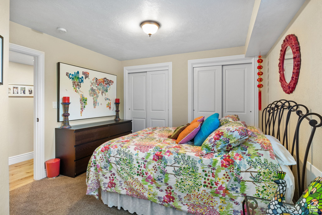 Carpeted bedroom with two closets and baseboards