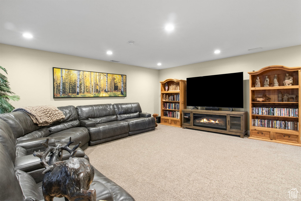 Carpeted living area featuring recessed lighting and a glass covered fireplace