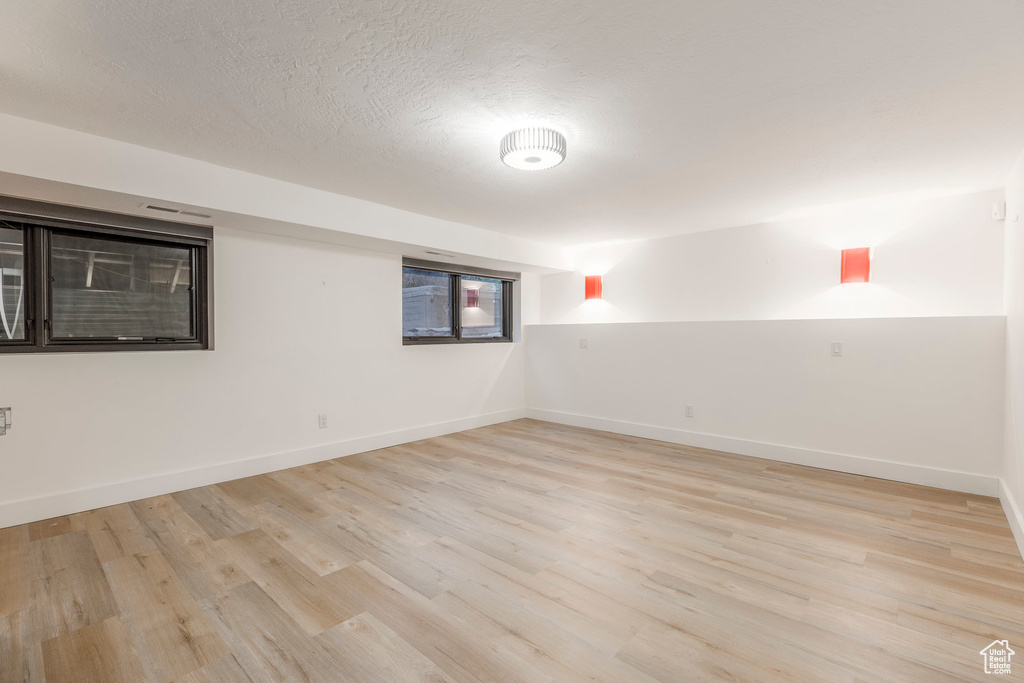 Empty room with light wood finished floors and a textured ceiling