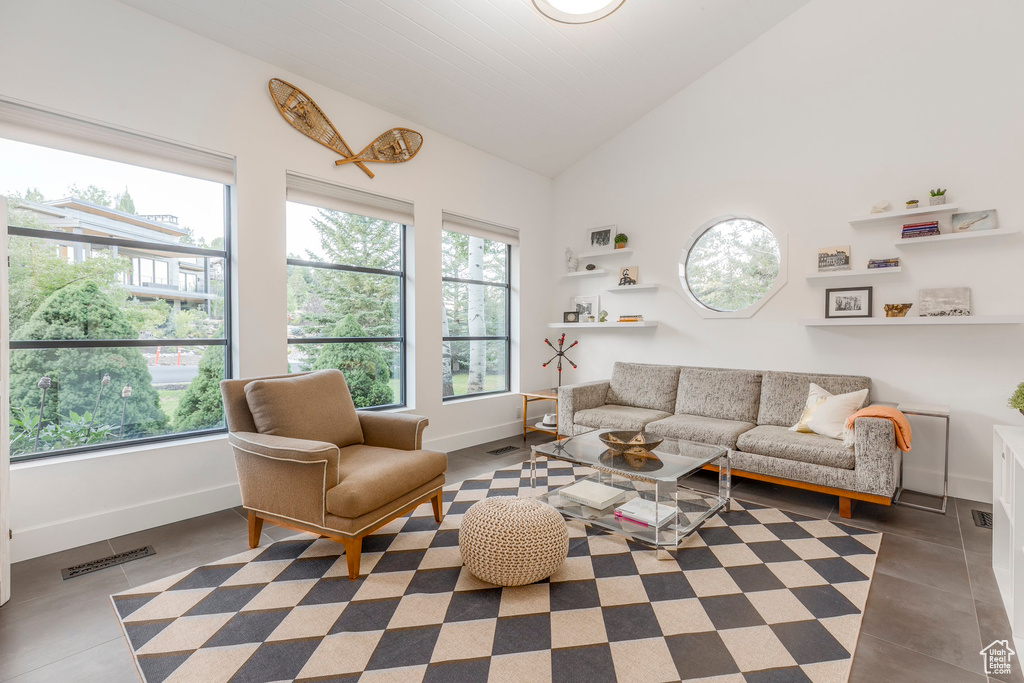 Tiled living room with baseboards and high vaulted ceiling