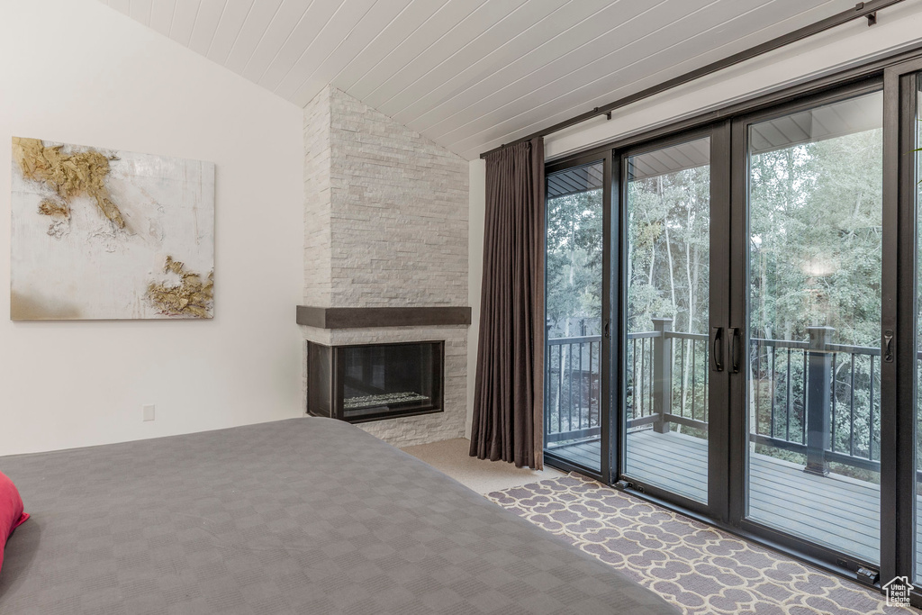 Unfurnished living room featuring vaulted ceiling, a stone fireplace, and carpet floors