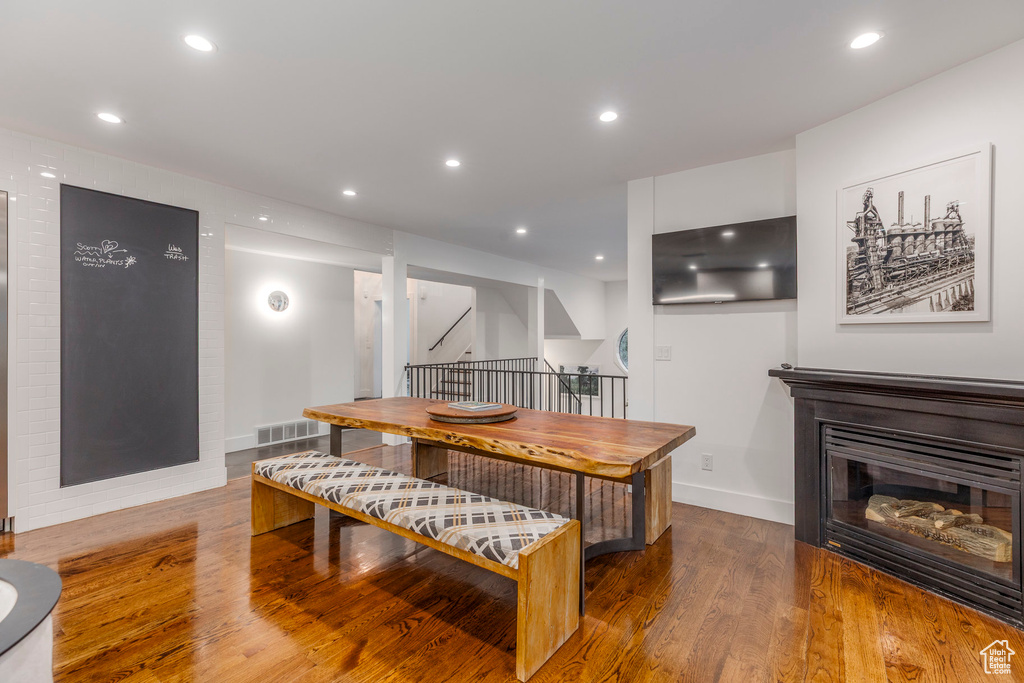 Dining room with wood finished floors, a glass covered fireplace, and recessed lighting