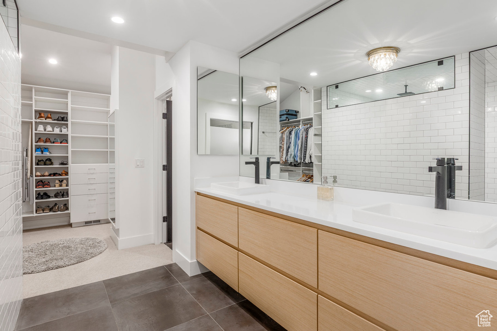 Full bath featuring a walk in closet, double vanity, a tile shower, tile patterned flooring, and recessed lighting