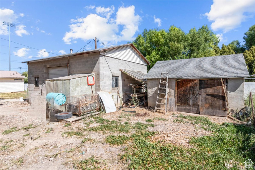 Rear view of property with concrete block siding, exterior structure, and an outdoor structure