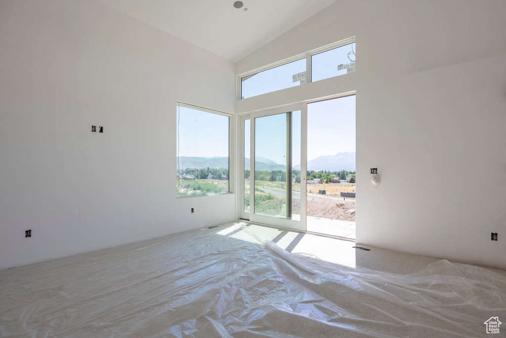 Unfurnished bedroom with a mountain view, access to outside, and high vaulted ceiling