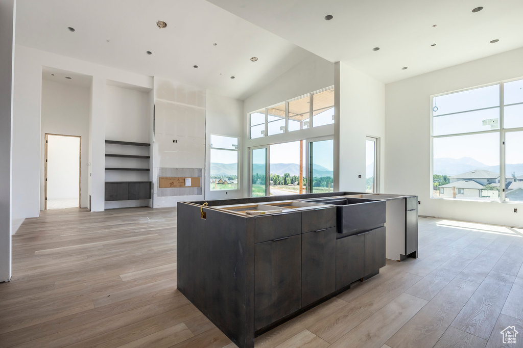 Kitchen featuring modern cabinets, light wood finished floors, a center island, a mountain view, and a towering ceiling