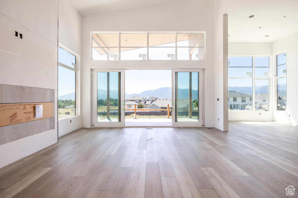 Unfurnished living room with a mountain view, wood finished floors, healthy amount of natural light, and a towering ceiling