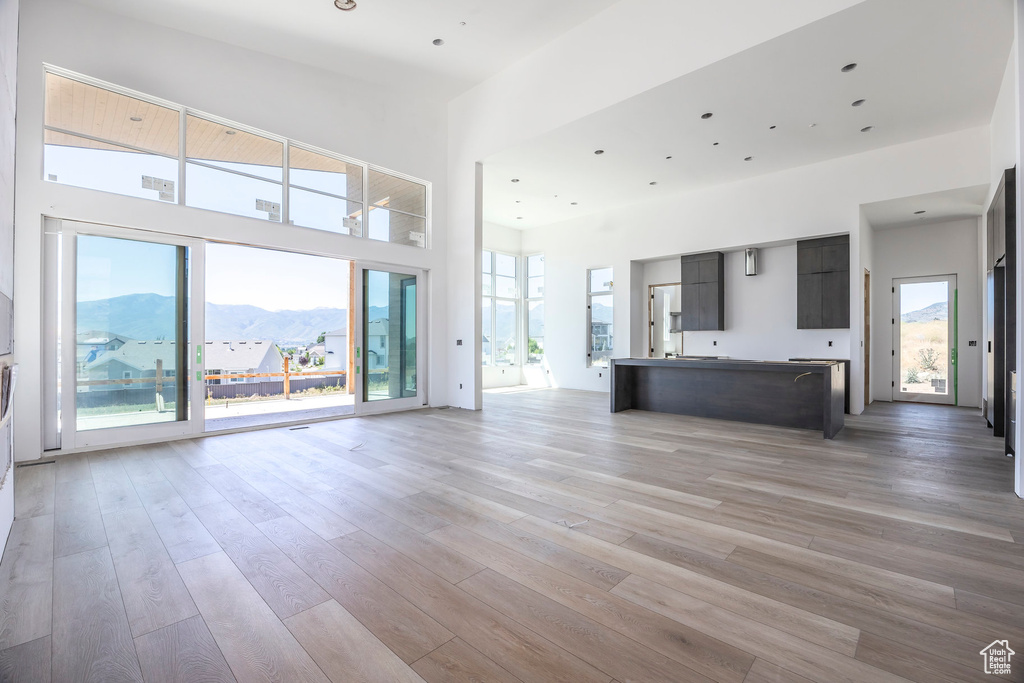 Unfurnished living room with a mountain view, light wood finished floors, and a high ceiling