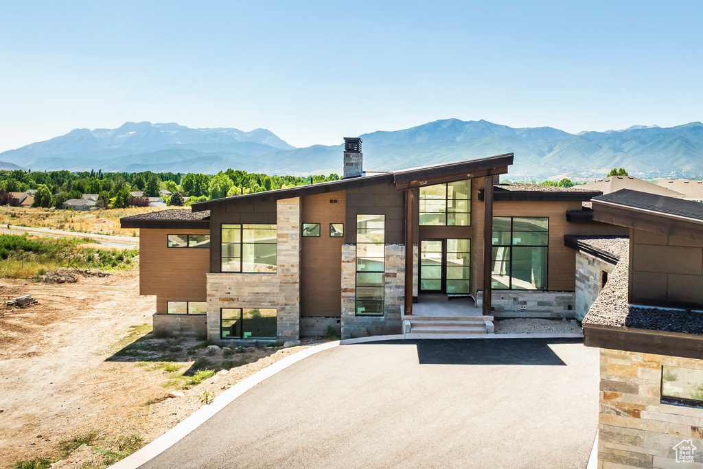 View of front of home featuring a mountain view, a chimney, and stone siding