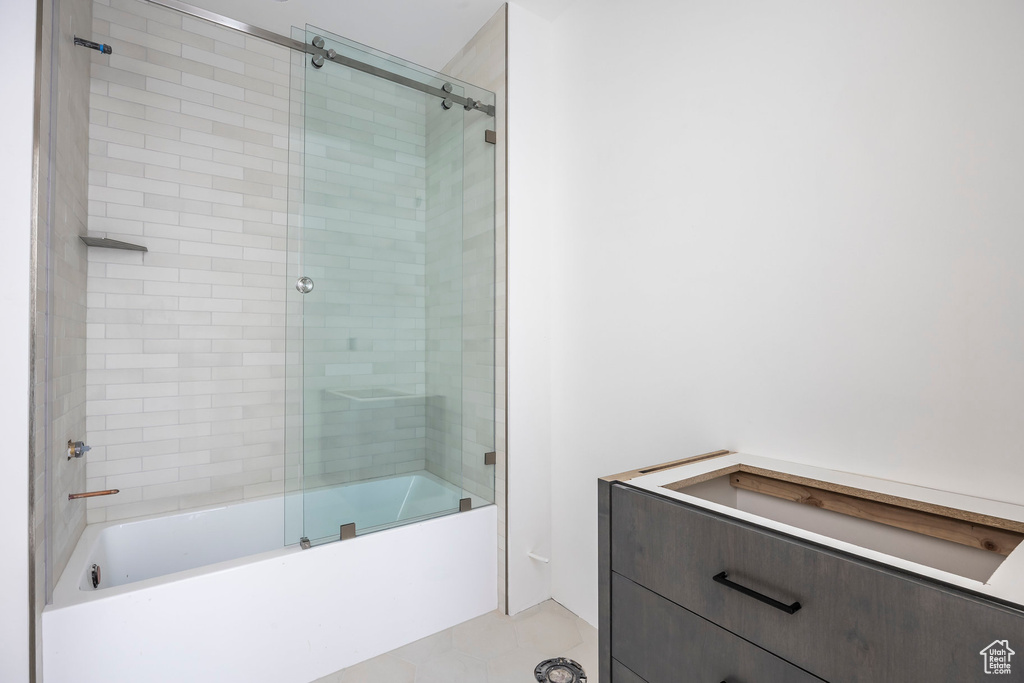 Full bath with enclosed tub / shower combo and tile patterned flooring