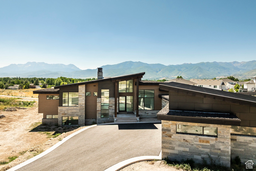 Contemporary home featuring a mountain view, stone siding, and a chimney