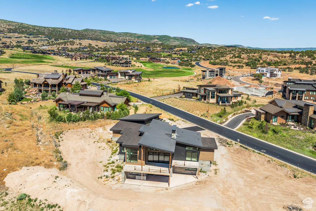 Aerial perspective of suburban area featuring a mountainous background and a local golf course