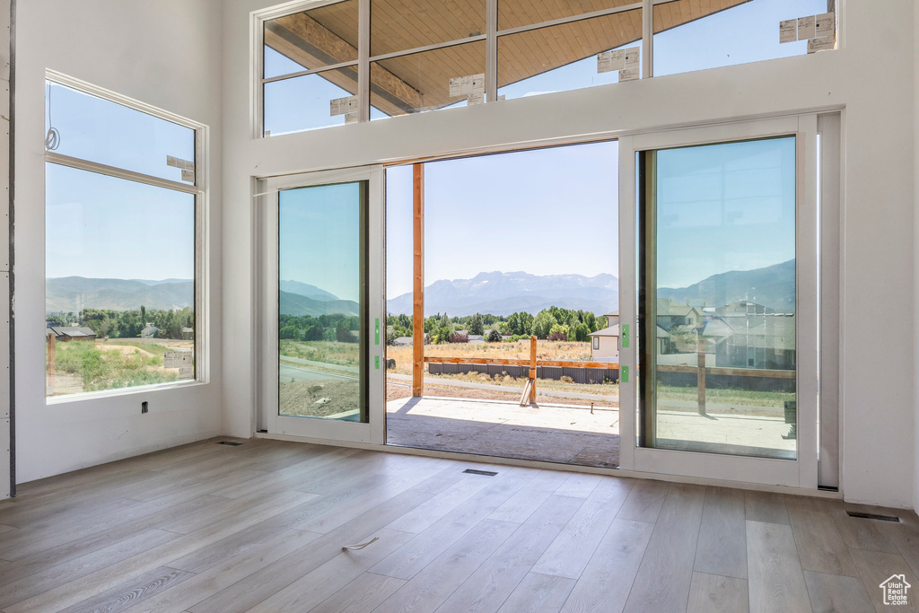 Empty room featuring a high ceiling, a mountain view, plenty of natural light, and wood finished floors