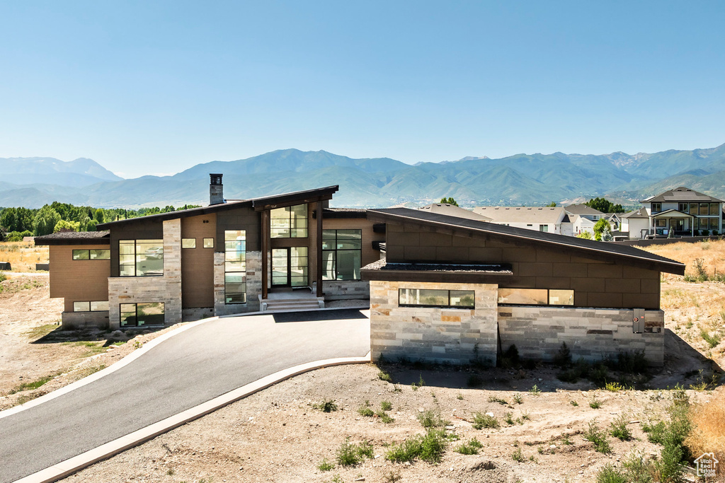 Contemporary home with a mountain view, a chimney, and stone siding