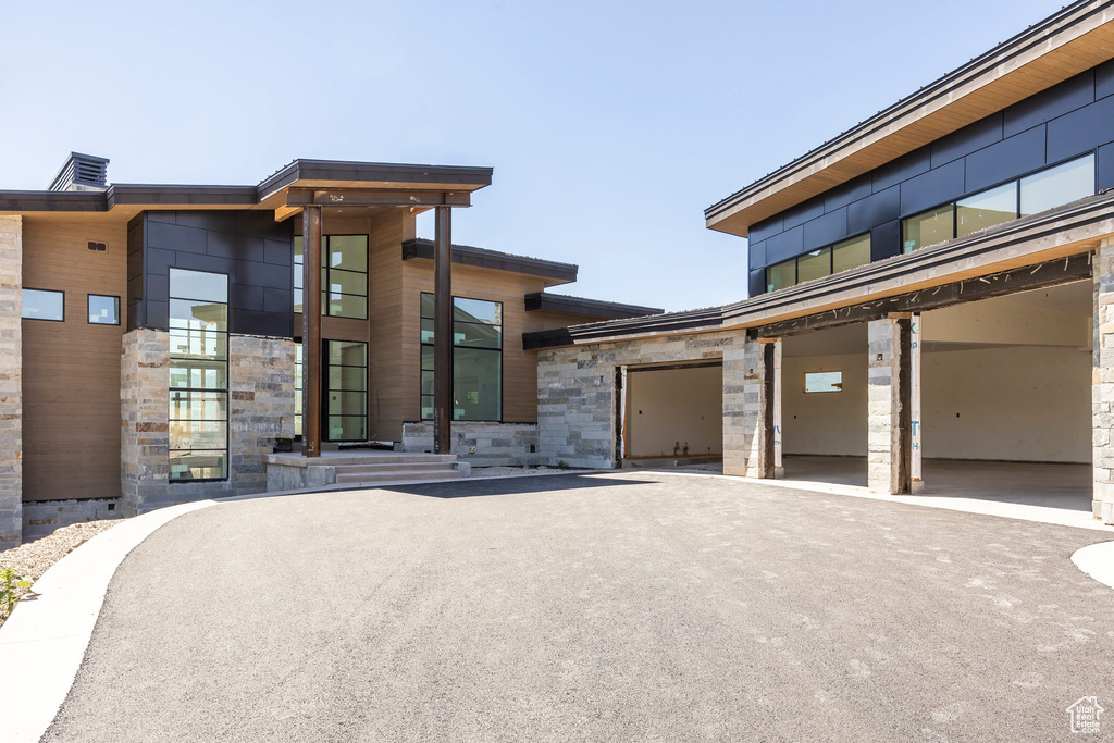 Contemporary home featuring stone siding, driveway, and a garage
