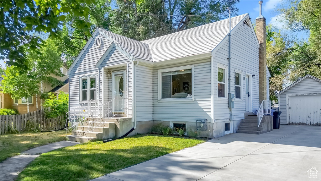 Bungalow-style house featuring a chimney, an outdoor structure, concrete driveway, and a detached garage