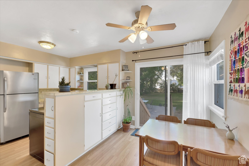 Kitchen featuring freestanding refrigerator, open shelves, a peninsula, and plenty of natural light