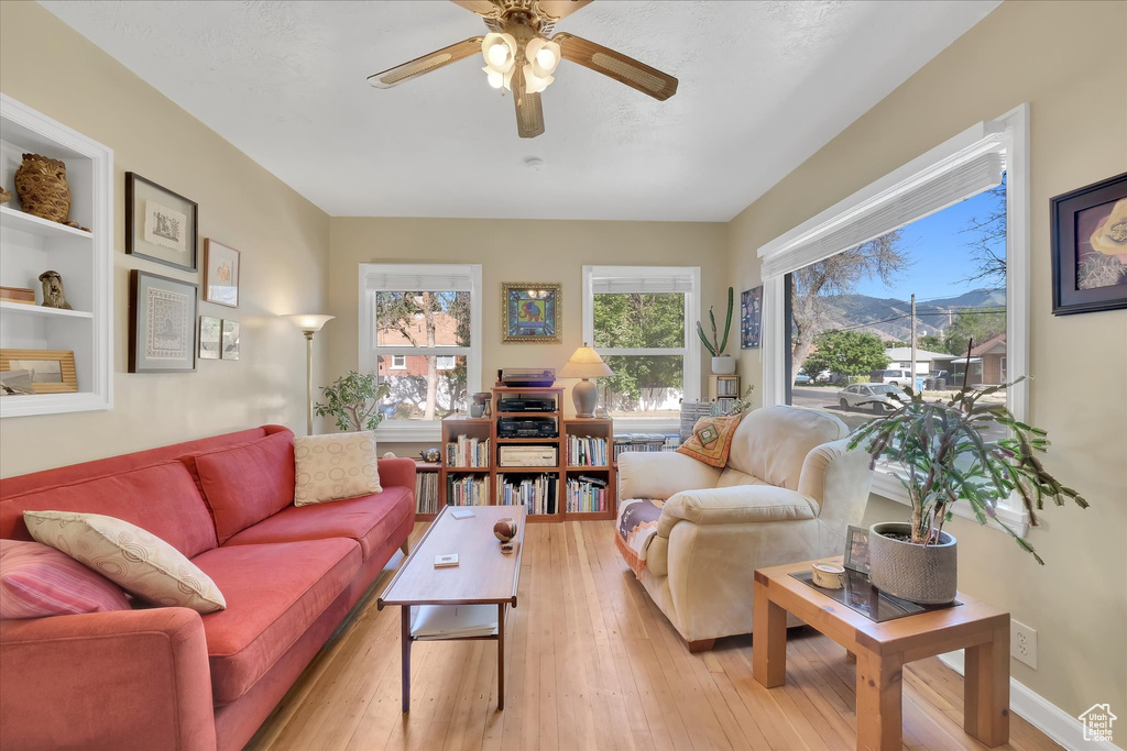 Living area with a ceiling fan, light wood-type flooring, and a mountain view