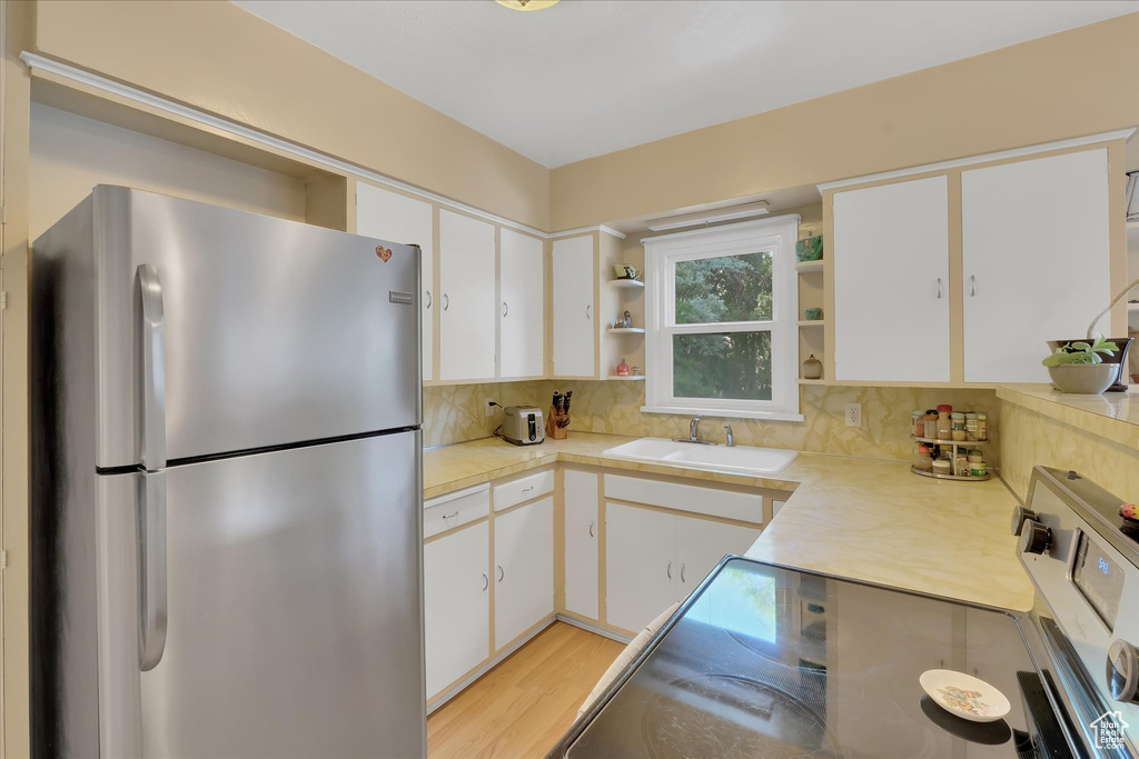 Kitchen with freestanding refrigerator, open shelves, electric range, and light countertops