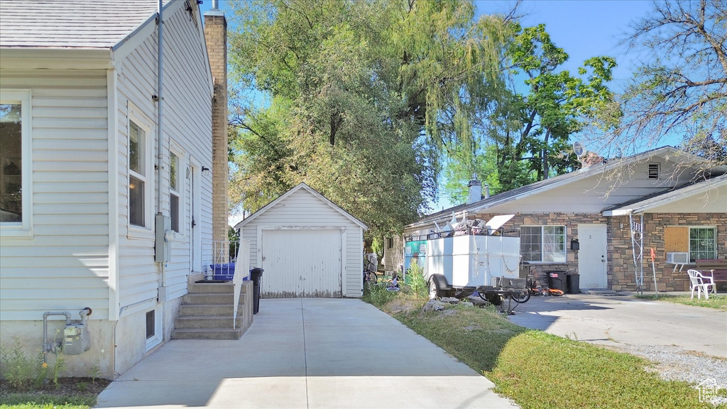 View of property exterior featuring driveway, a detached garage, and an outdoor structure