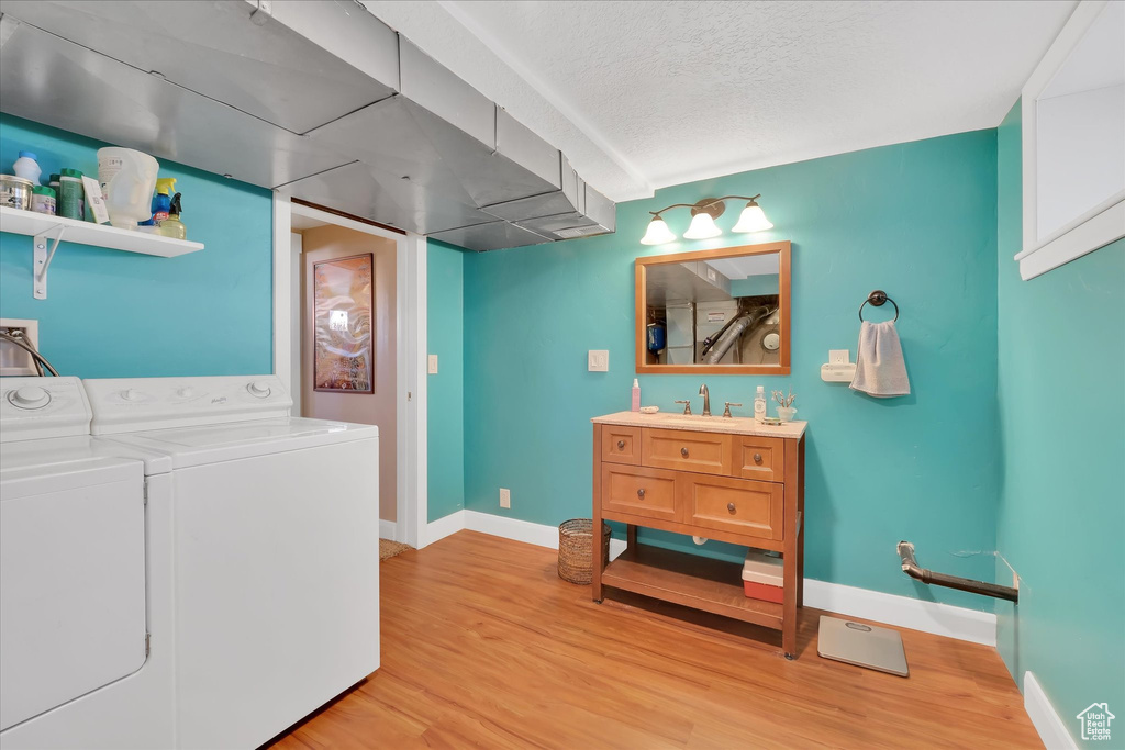Laundry area with washer and clothes dryer and light wood-style floors