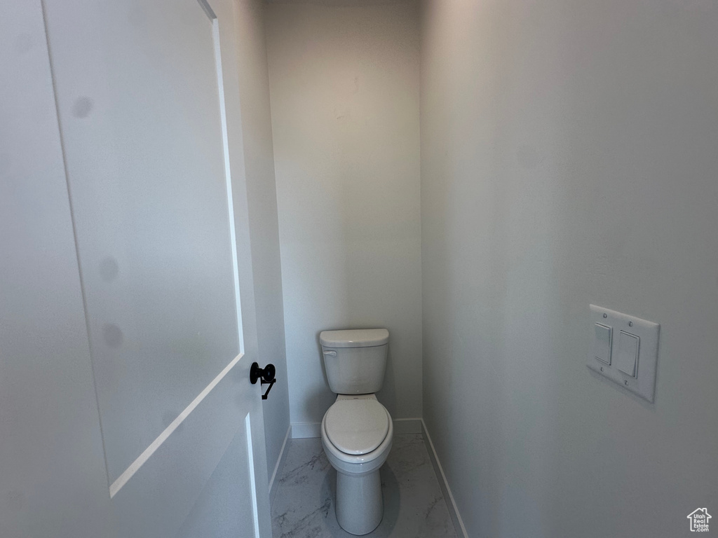 Bathroom with marble look tile flooring and toilet