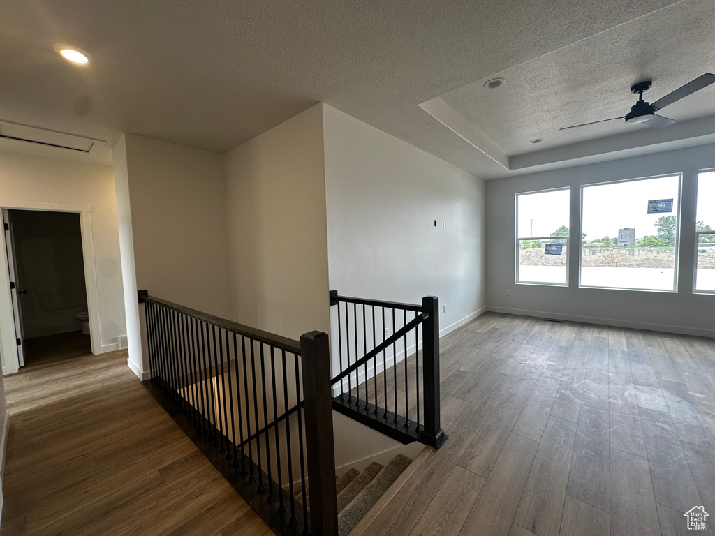 Corridor with an upstairs landing, wood finished floors, attic access, a textured ceiling, and recessed lighting