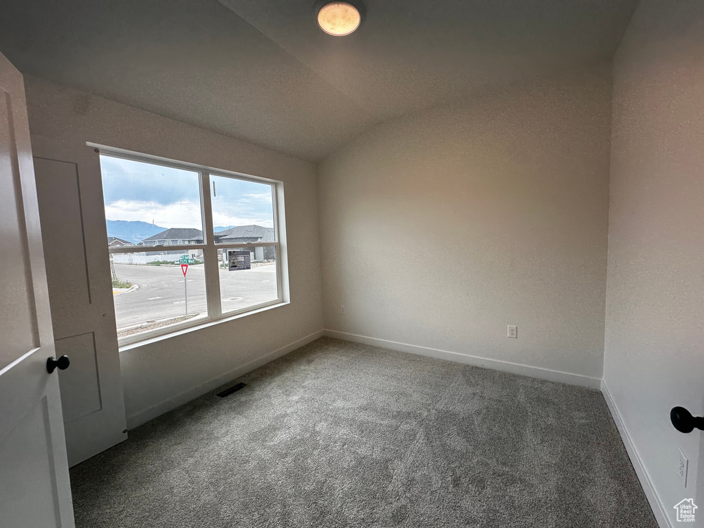 Empty room with carpet flooring and vaulted ceiling