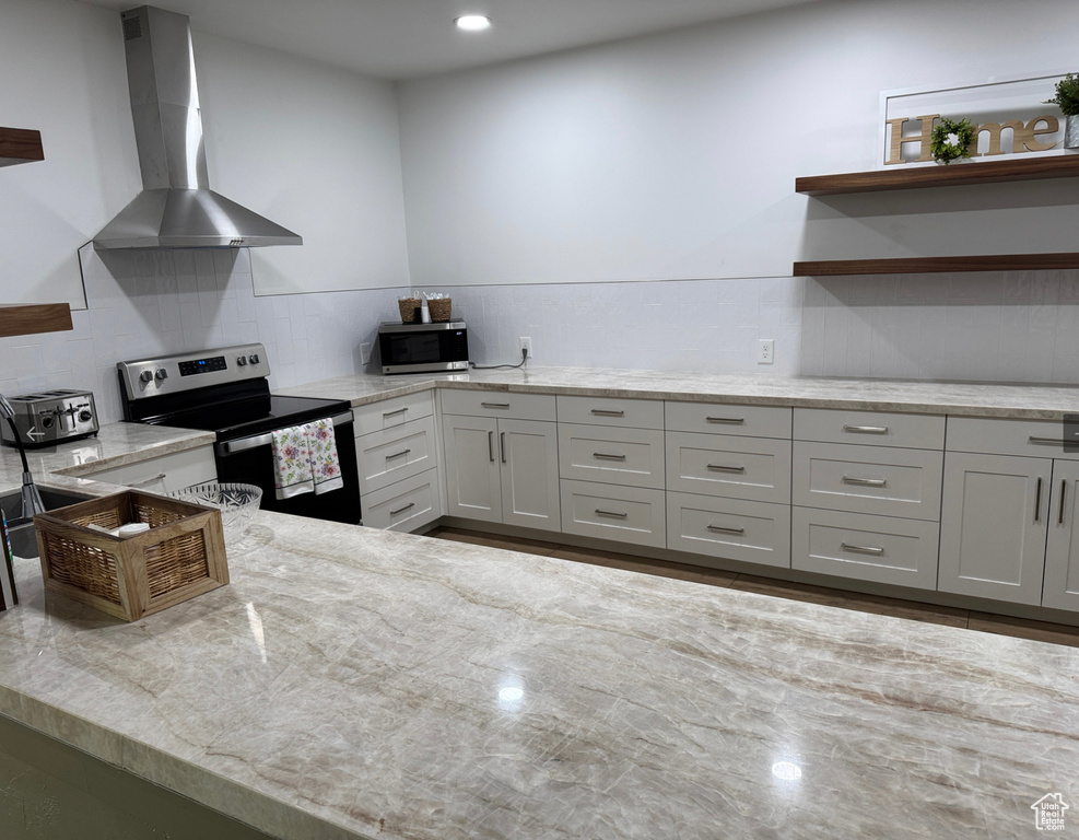 Kitchen featuring open shelves, wall chimney exhaust hood, appliances with stainless steel finishes, light stone counters, and backsplash