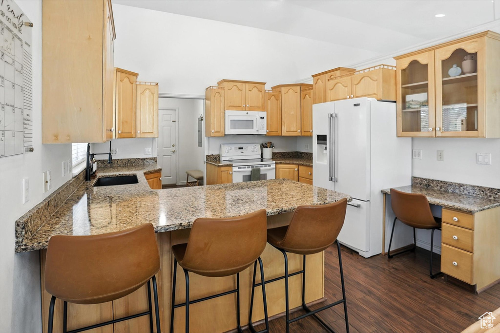 Kitchen with a peninsula, white appliances, glass insert cabinets, dark wood-style flooring, and light brown cabinets