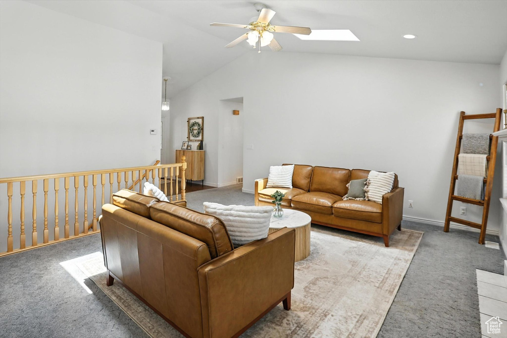 Living area with ceiling fan, lofted ceiling, a skylight, and light carpet