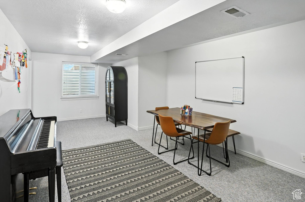 Dining area with light carpet and a textured ceiling