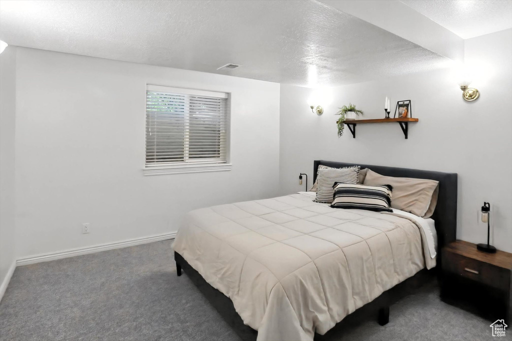 Carpeted bedroom featuring baseboards and a textured ceiling