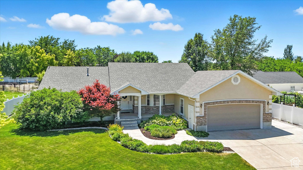 View of front of house with a garage, a porch, driveway, stucco siding, and stone siding