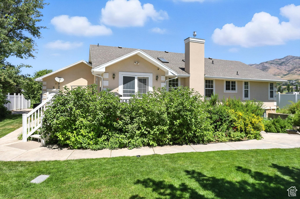 View of front of home with stucco siding, a chimney, and roof with shingles