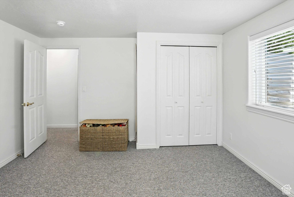 Unfurnished bedroom with carpet floors, multiple windows, and a closet