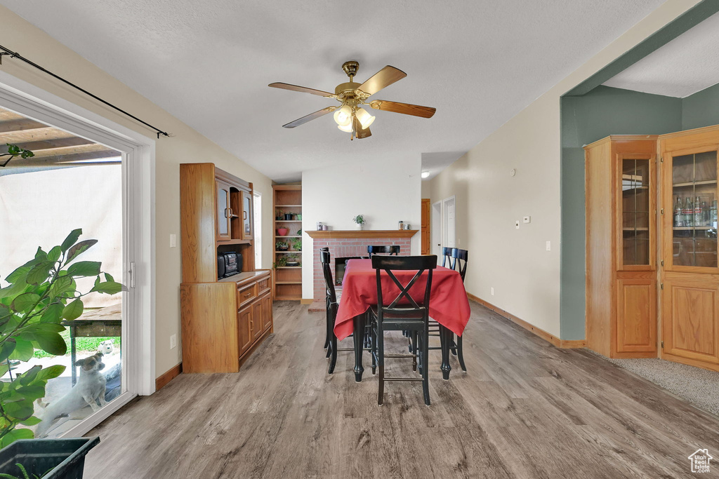 Dining room featuring a ceiling fan, light wood finished floors, healthy amount of natural light, and vaulted ceiling