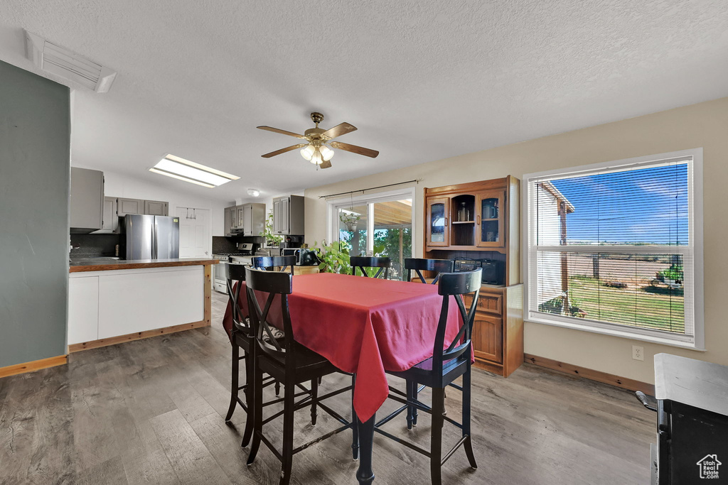 Dining room featuring light wood-style flooring, a textured ceiling, and ceiling fan