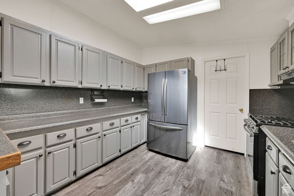 Kitchen featuring appliances with stainless steel finishes, decorative backsplash, gray cabinets, and light wood-style flooring