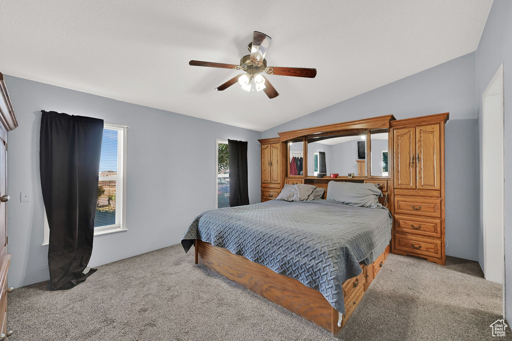 Bedroom with light colored carpet, vaulted ceiling, and ceiling fan