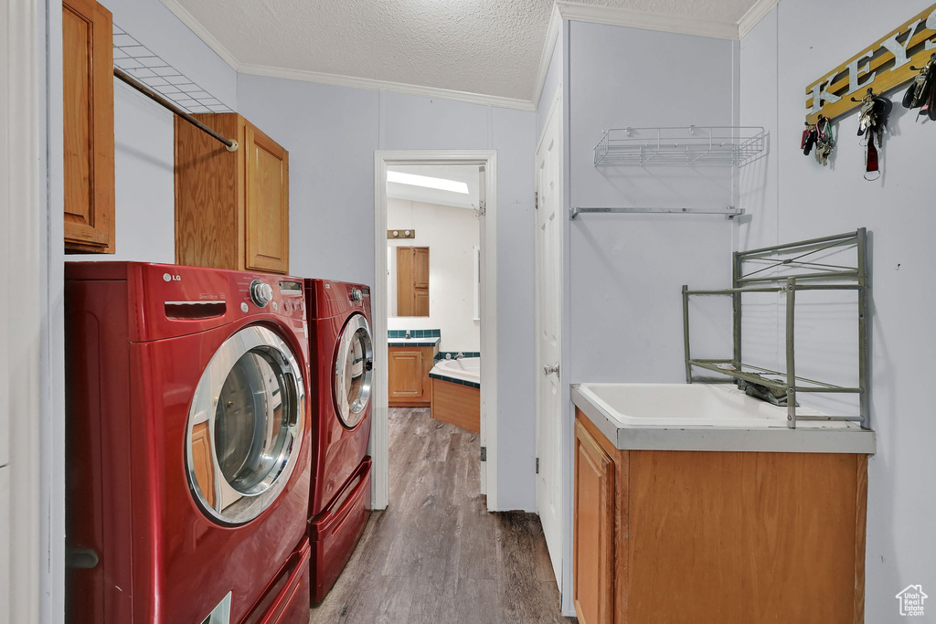 Laundry room with cabinet space, washer and dryer, ornamental molding, and wood finished floors