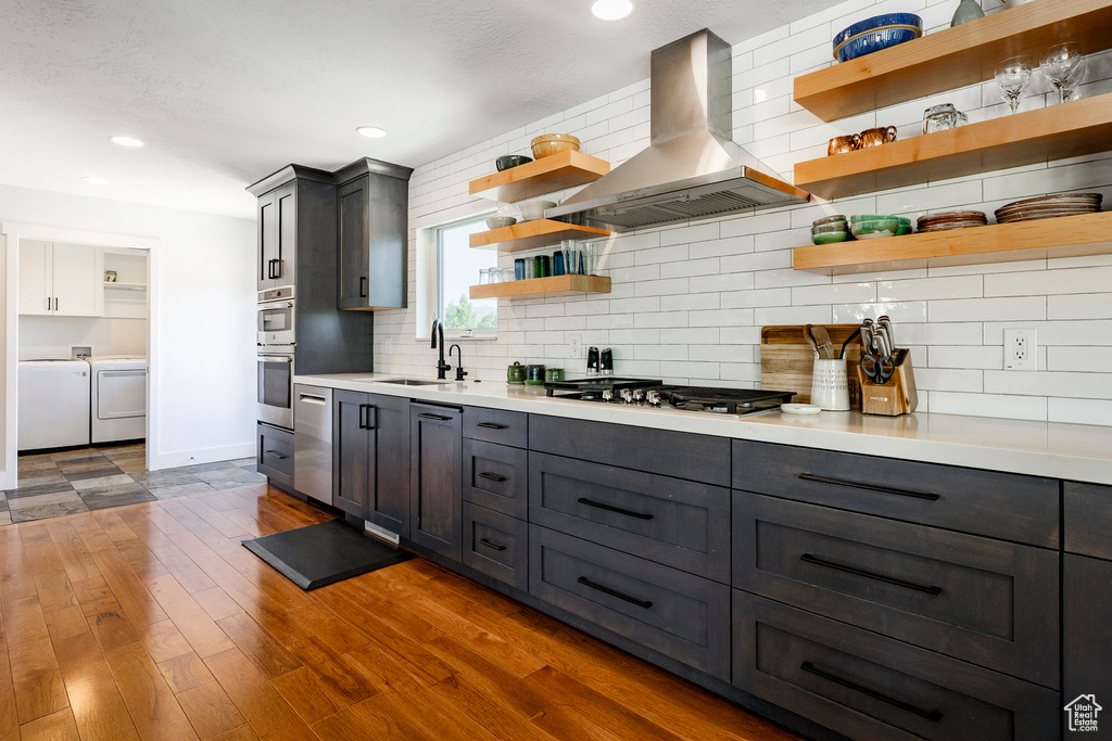 Kitchen featuring open shelves, washer and dryer, island range hood, light countertops, and decorative backsplash