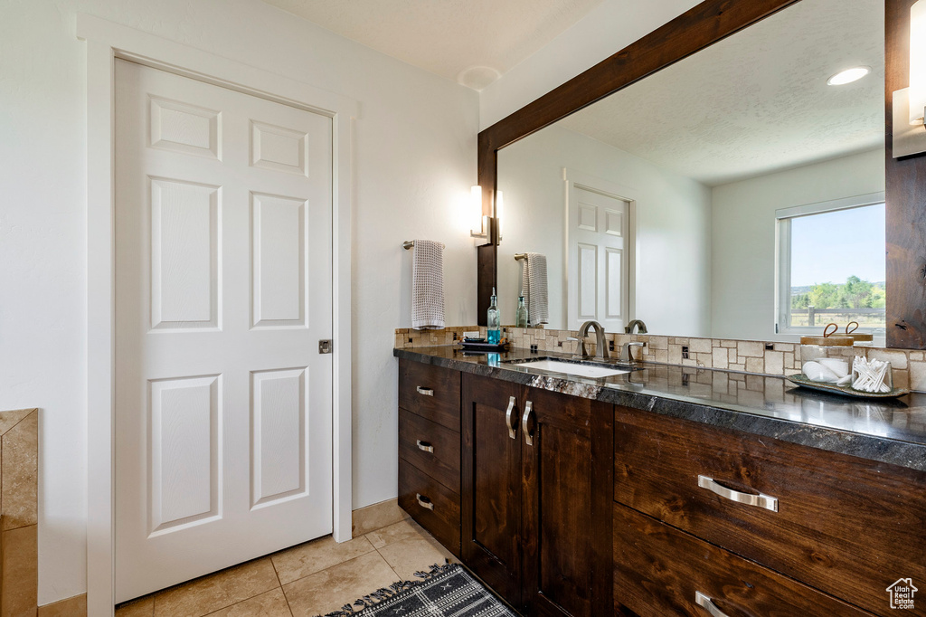Bathroom featuring vanity, tile patterned flooring, and tasteful backsplash