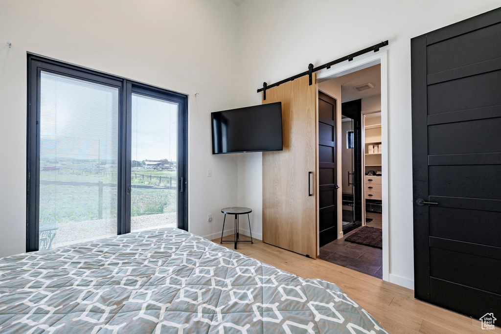 Bedroom with wood finished floors, access to exterior, and a barn door