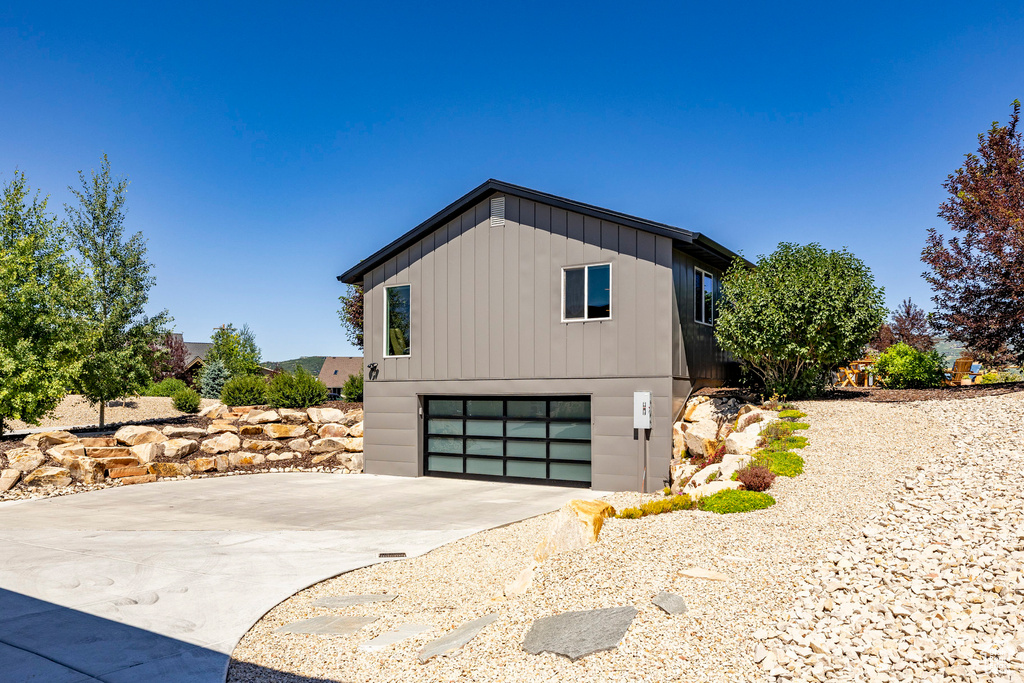 View of side of home featuring driveway, board and batten siding, and a garage